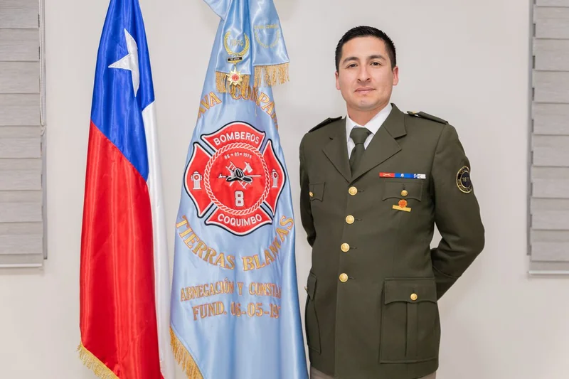 Persona uniformada junto a las banderas en una ceremonia